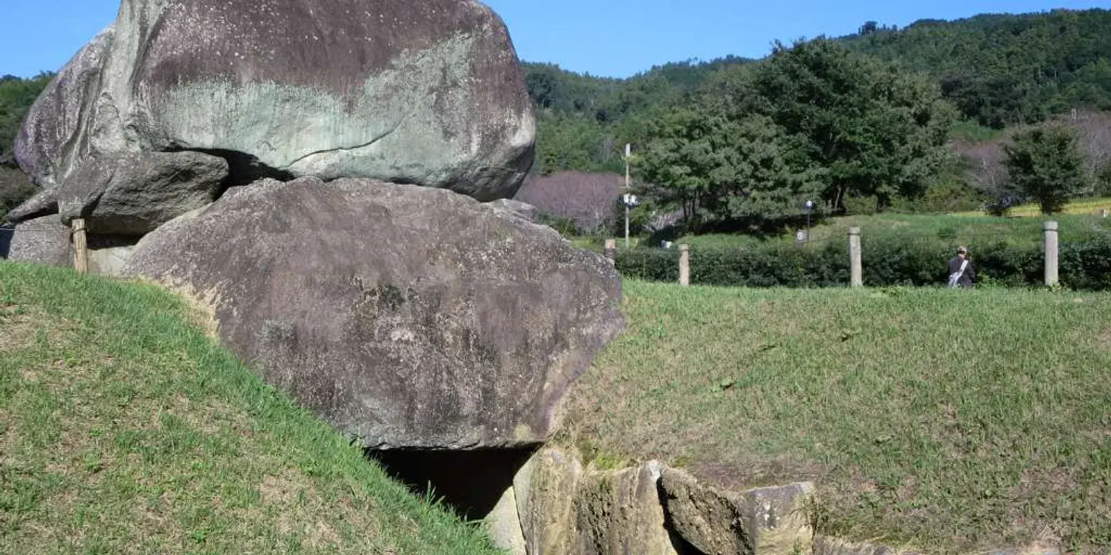 The exposed megalithic stone chamber of Ishibutai Kofun rising from a grassy mound in Asuka village