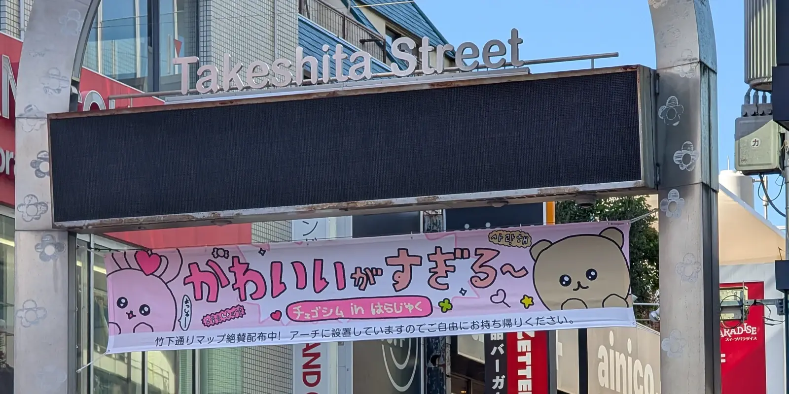 The entrance arch and sign of Takeshita Street in Harajuku, beneath a pink kawaii banner