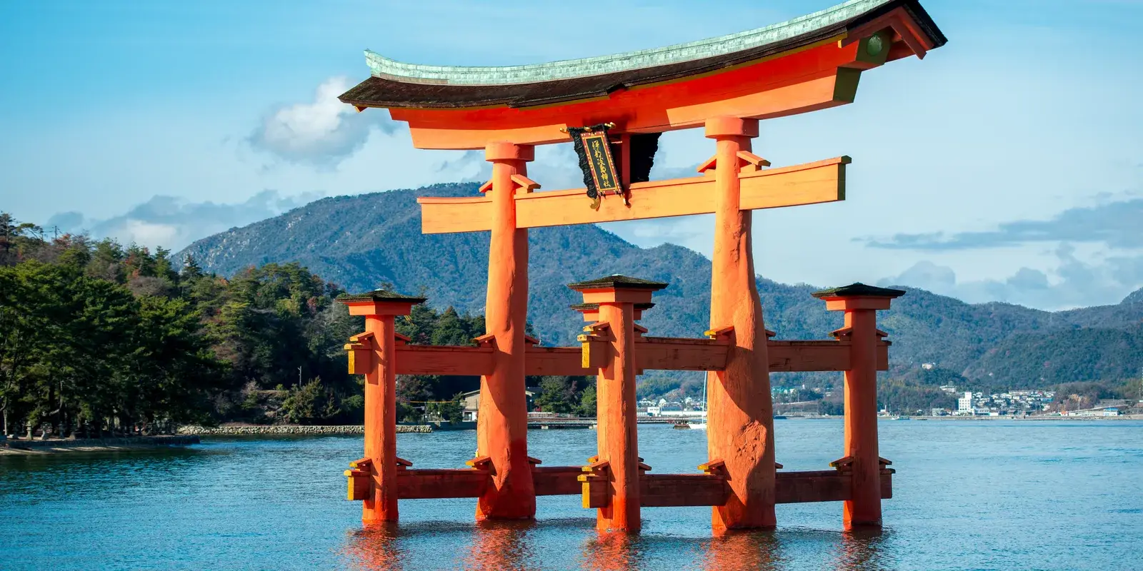 The floating torii gate of Itsukushima Shrine on Miyajima, standing in the water at high tide against forested hills
