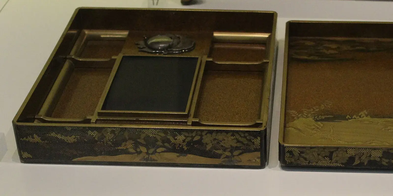 Open Japanese lacquerware writing box (suzuribako) with an inkstone, silver waterdropper, and gold maki-e brush trays, used in calligraphy