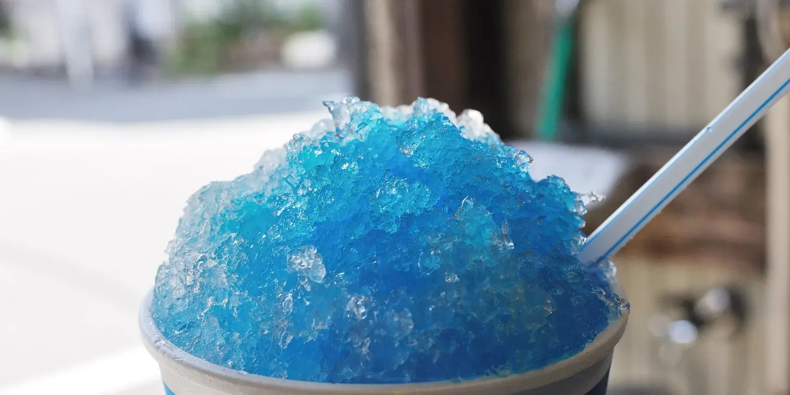 A cup of bright blue shaved ice (kakigori), a classic Japanese summer treat, on a sunny day
