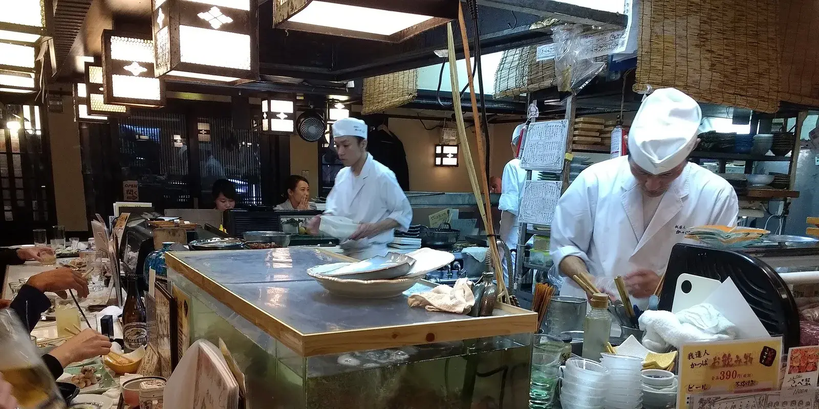 Chefs preparing dishes behind the counter of a traditional izakaya restaurant in Gion, Kyoto