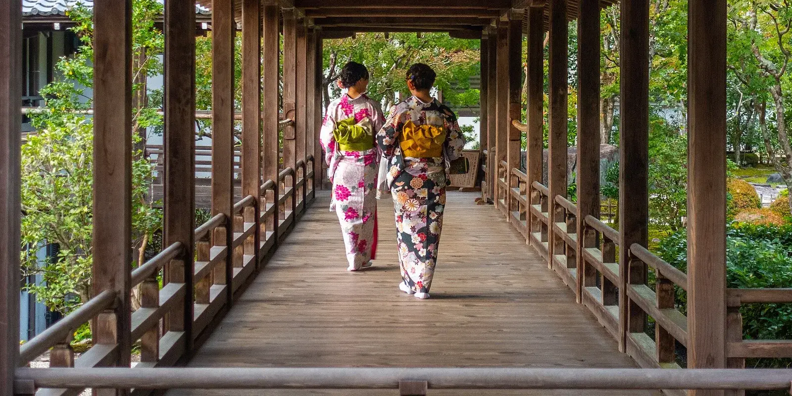 Two visitors in colorful kimono walking away from the camera through a traditional wooden corridor at Nanzen-ji temple in Kyoto