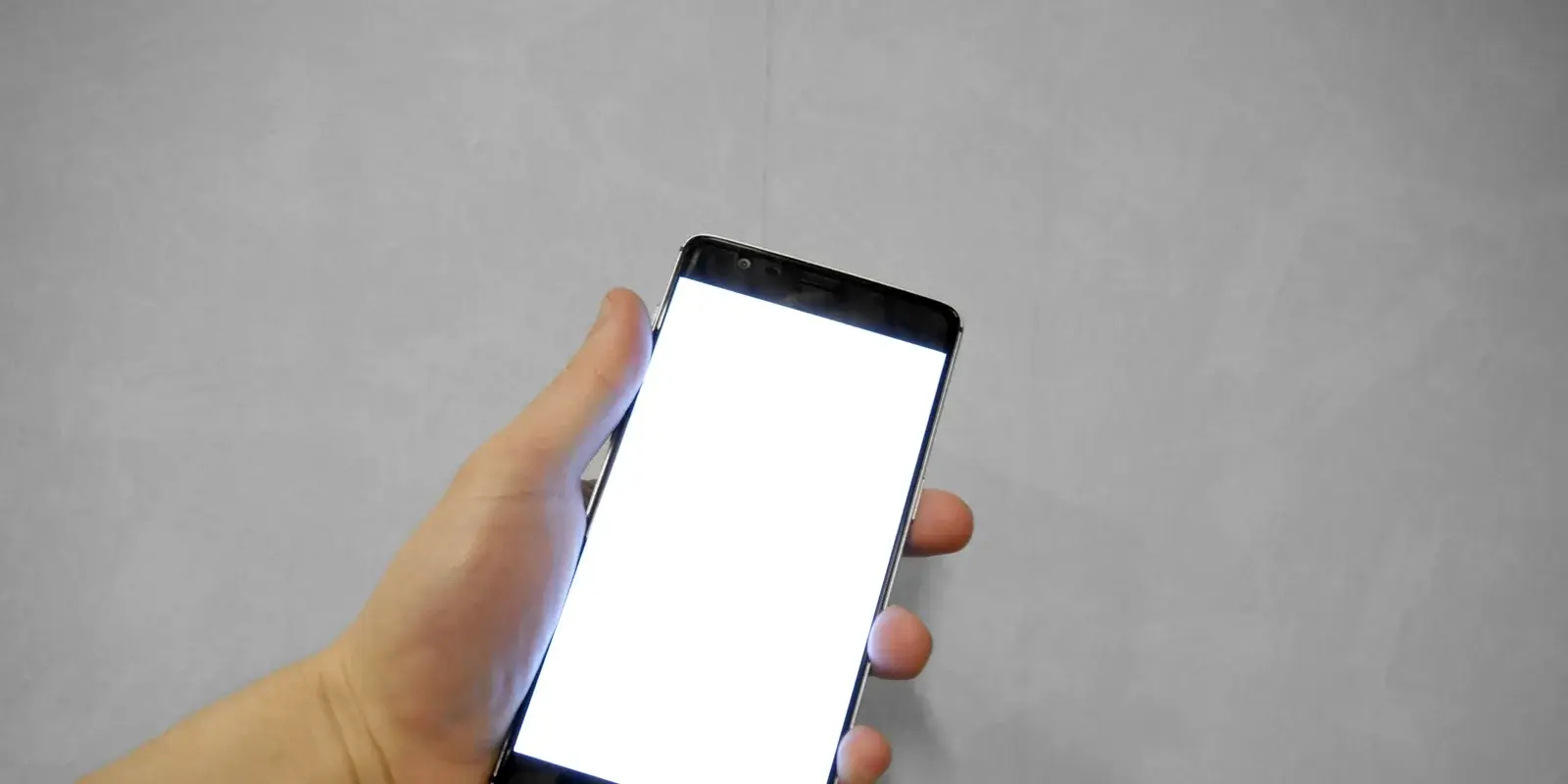 A hand holding up a smartphone with the screen facing forward, ready to show on-screen text