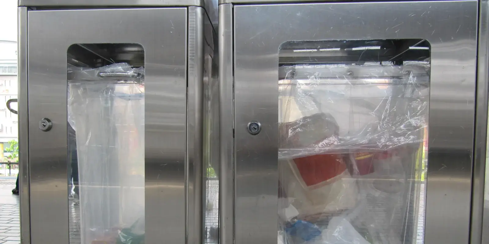 See-through stainless-steel recycle and trash bins on a train station platform in Japan, the sorted bins where travelers dispose of their waste