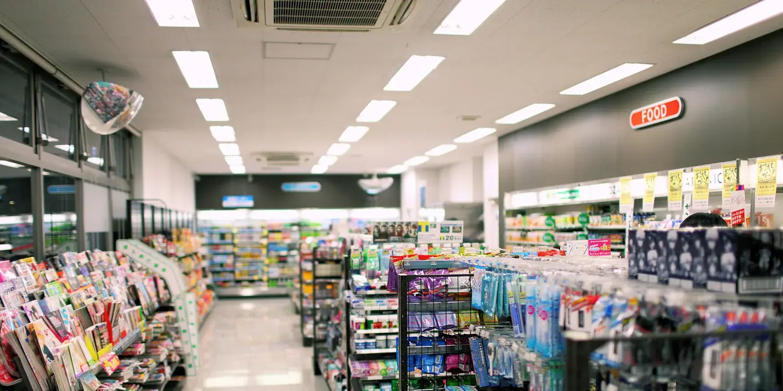Interior of a Japanese convenience store in Tokyo, brightly lit aisles of stocked shelves with no people