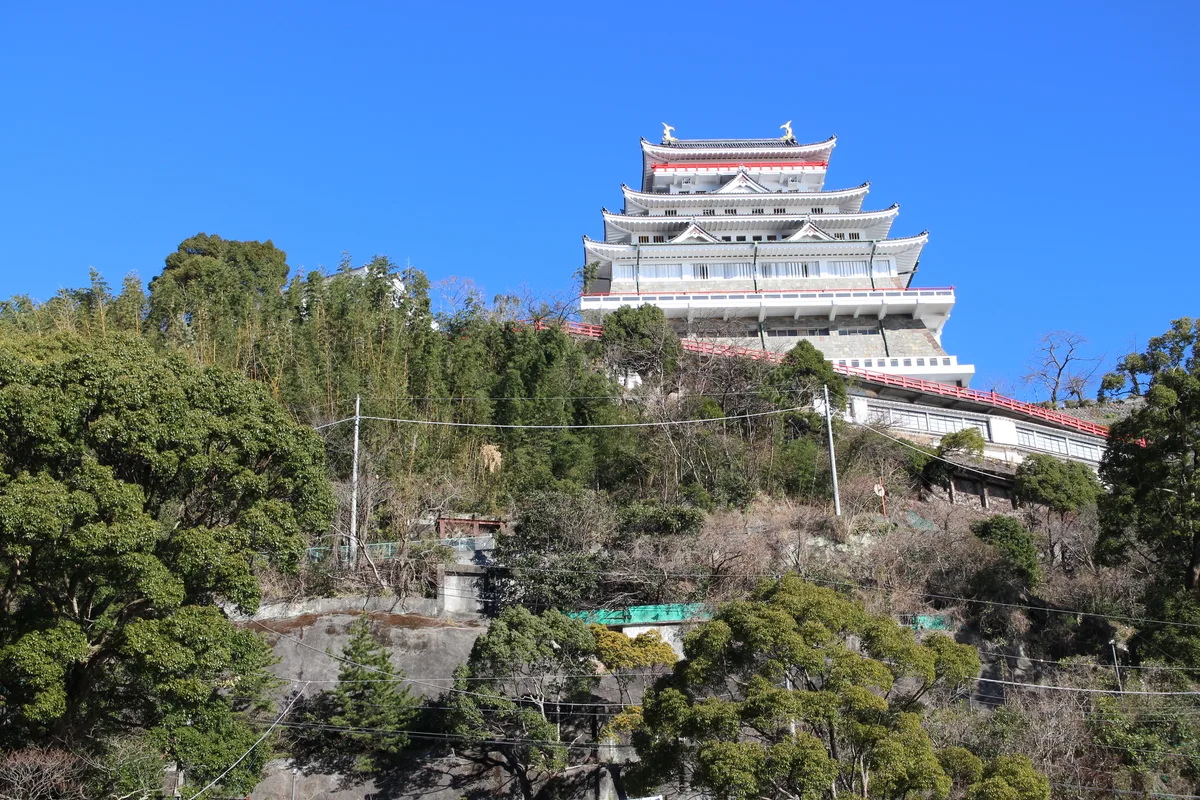 La torre a più piani del Castello di Atami vista dal basso della collina, contro un cielo azzurro terso