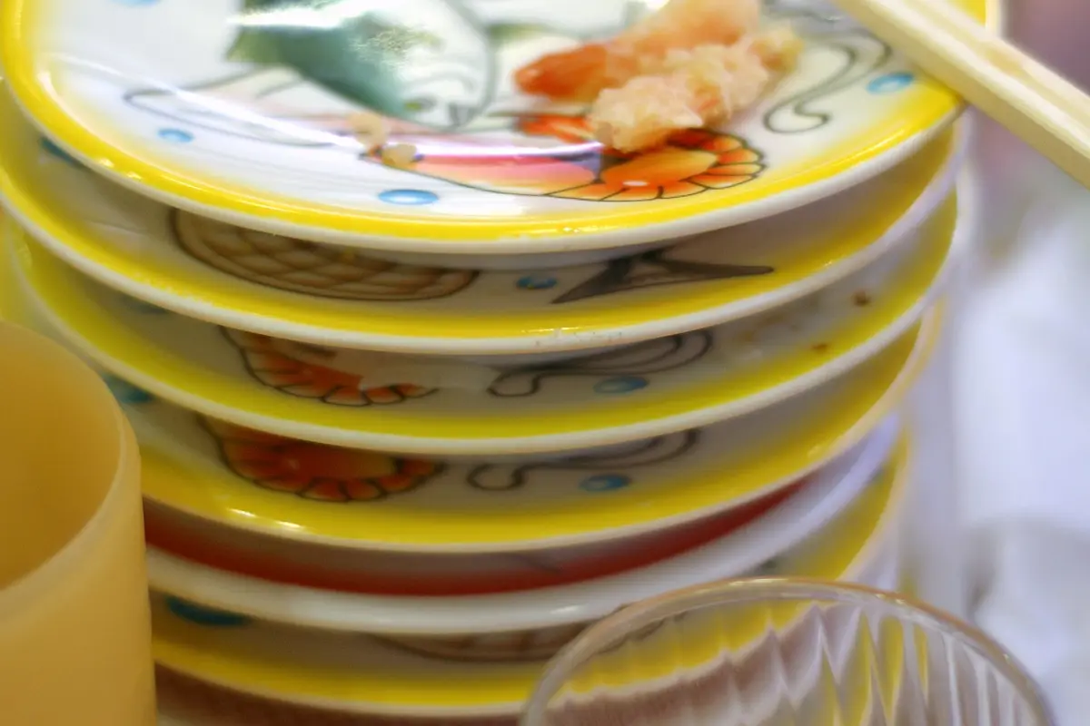 A stack of finished plates on a restaurant table, with chopsticks laid across the top