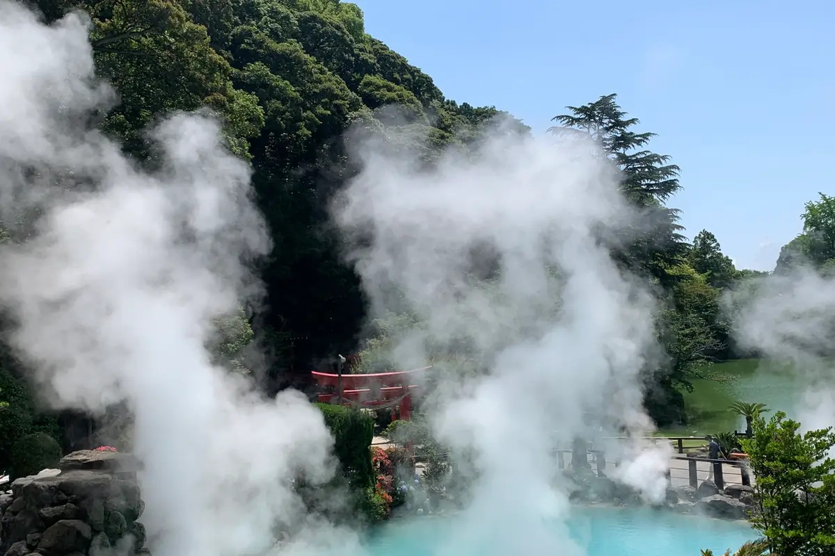 Umi Jigoku in Beppu: a turquoise pond under thick white steam, with a small red shrine gate on the far bank