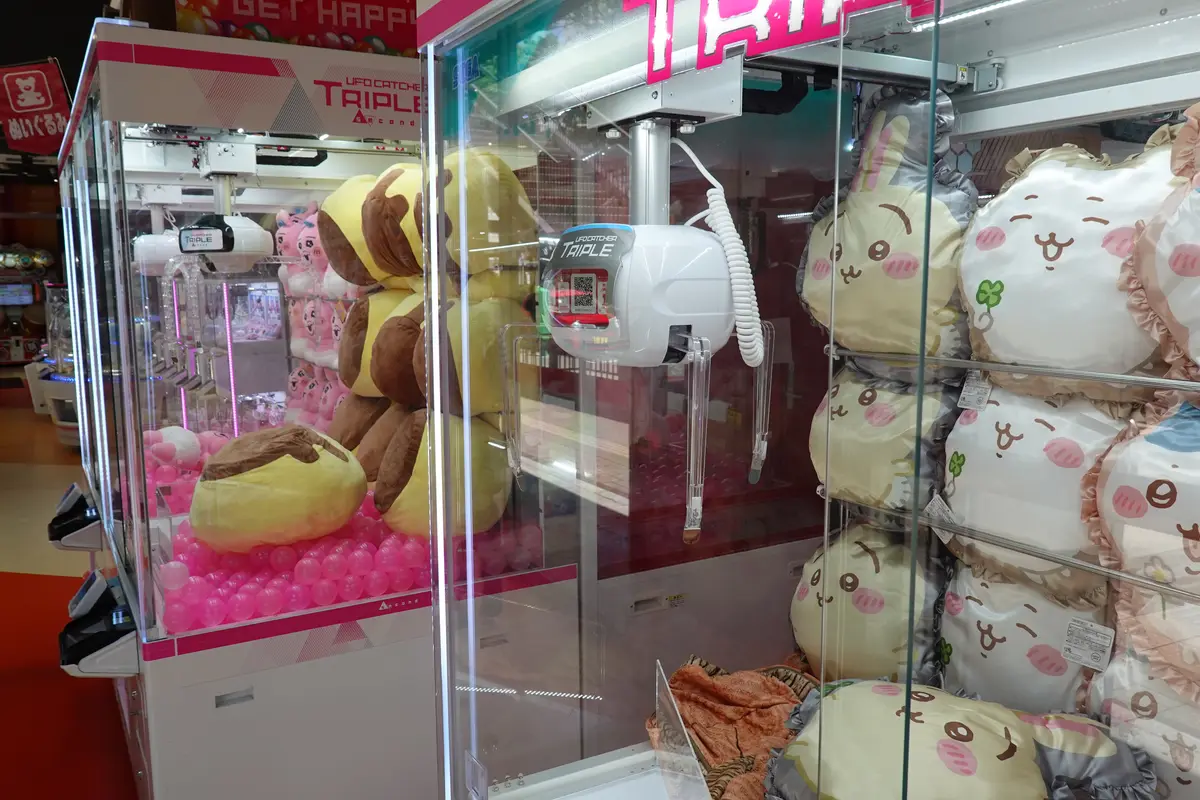 Due macchine con la pinza in una sala giochi giapponese, con la pinza sospesa sopra i peluche impilati dietro il vetro