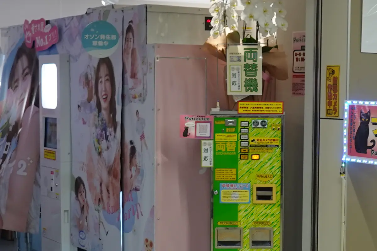 Un angolo purikura in Giappone, con le cabine rivestite di pannelli fotografici, una tenda e un cambiamonete accanto