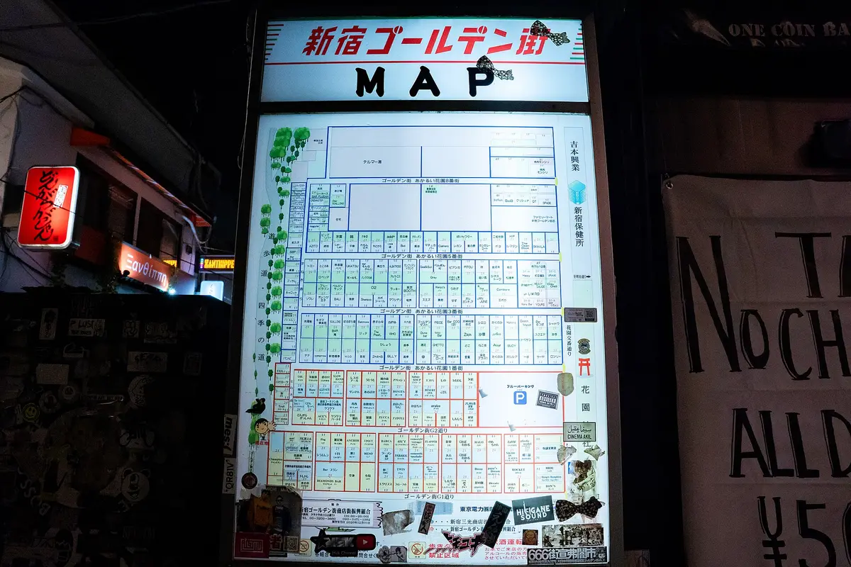 A lit street-map board of Shinjuku Golden Gai at night, showing the shops laid out lane by lane