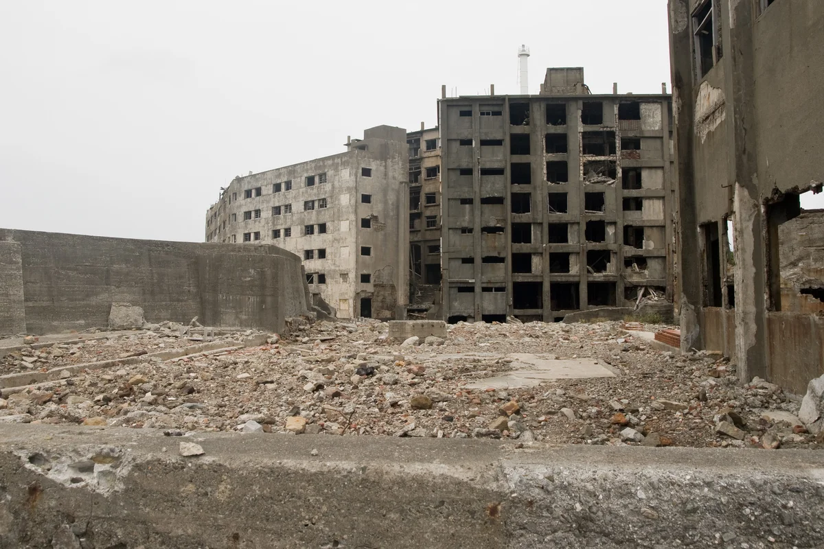 Building 30, a crumbling reinforced-concrete apartment block on Gunkanjima, seen among rubble and the collapsed floors of neighboring buildings