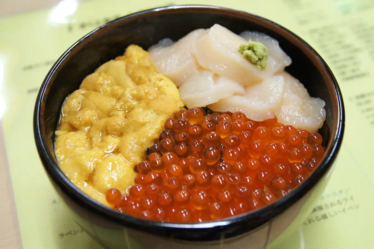 A seafood bowl from Hakodate's morning market: sea urchin, salmon roe and scallop laid over rice in a black lacquer bowl