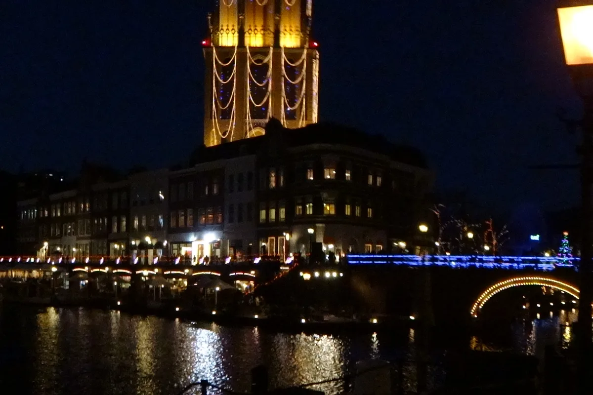 Huis Ten Bosch illuminated at night with colorful lights reflecting on the canal