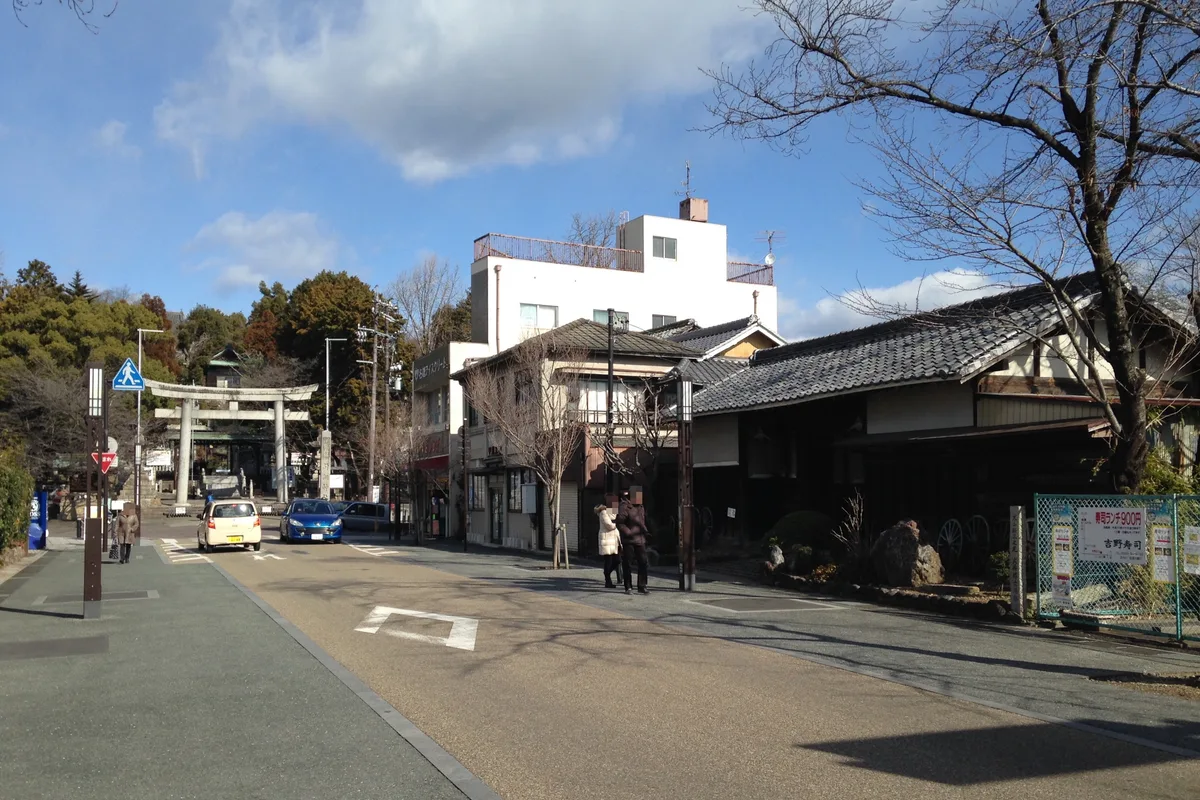 The castle-town approach street, with a shrine gate and an old tiled-roof storehouse