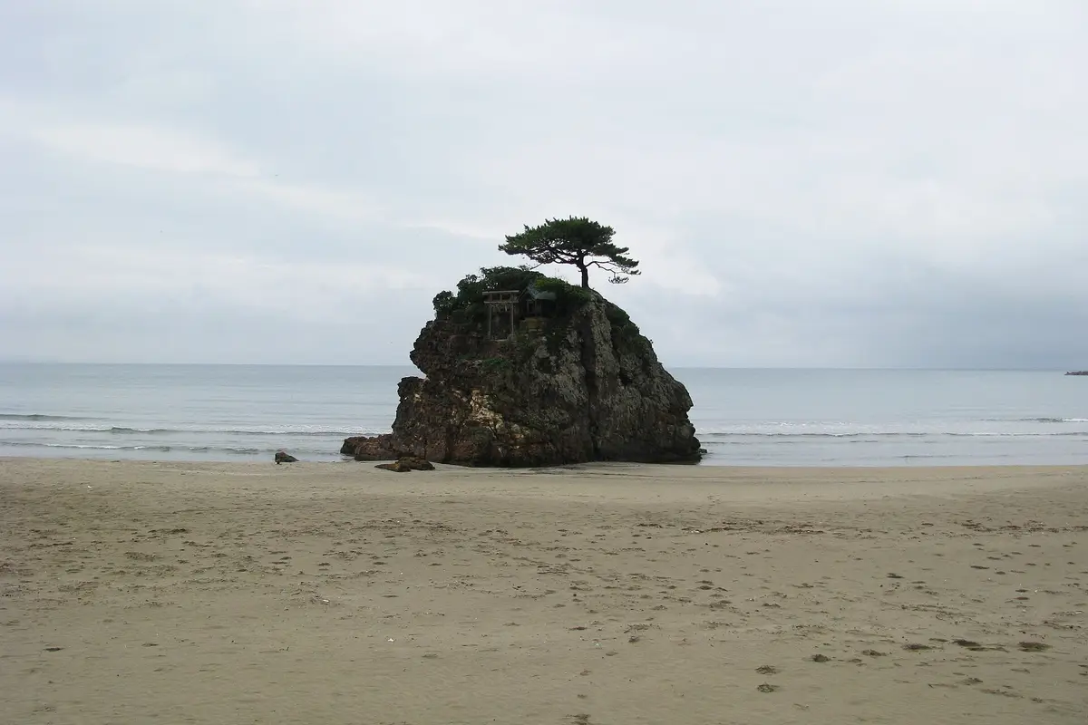L'ampia sabbia asciutta di Inasa Beach, con un isolotto roccioso sormontato da un piccolo torii dove si infrangono le onde