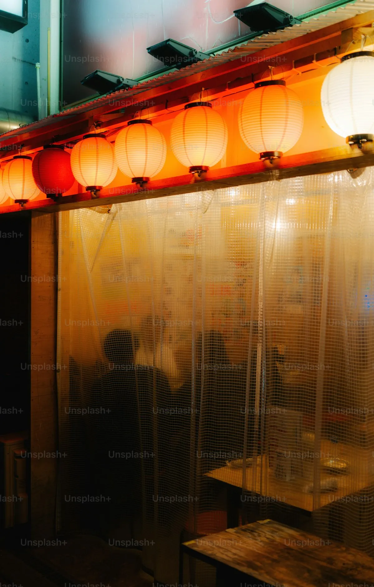 Warm lanterns mark the entrance — pushing through the curtain is half the adventure