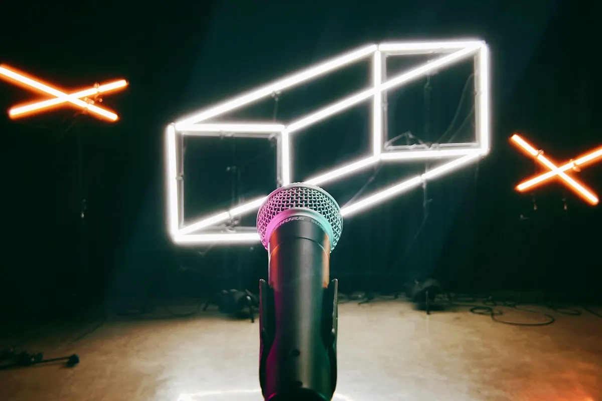 A microphone bathed in colorful neon light in a dark performance room