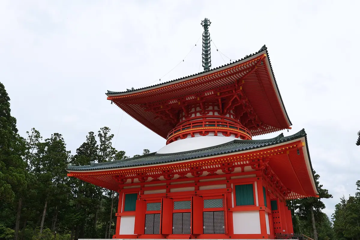 The vermilion Konpon Daito pagoda in the Danjo Garan precinct on Koyasan, its two tiers of curved roofs rising above the surrounding cedars