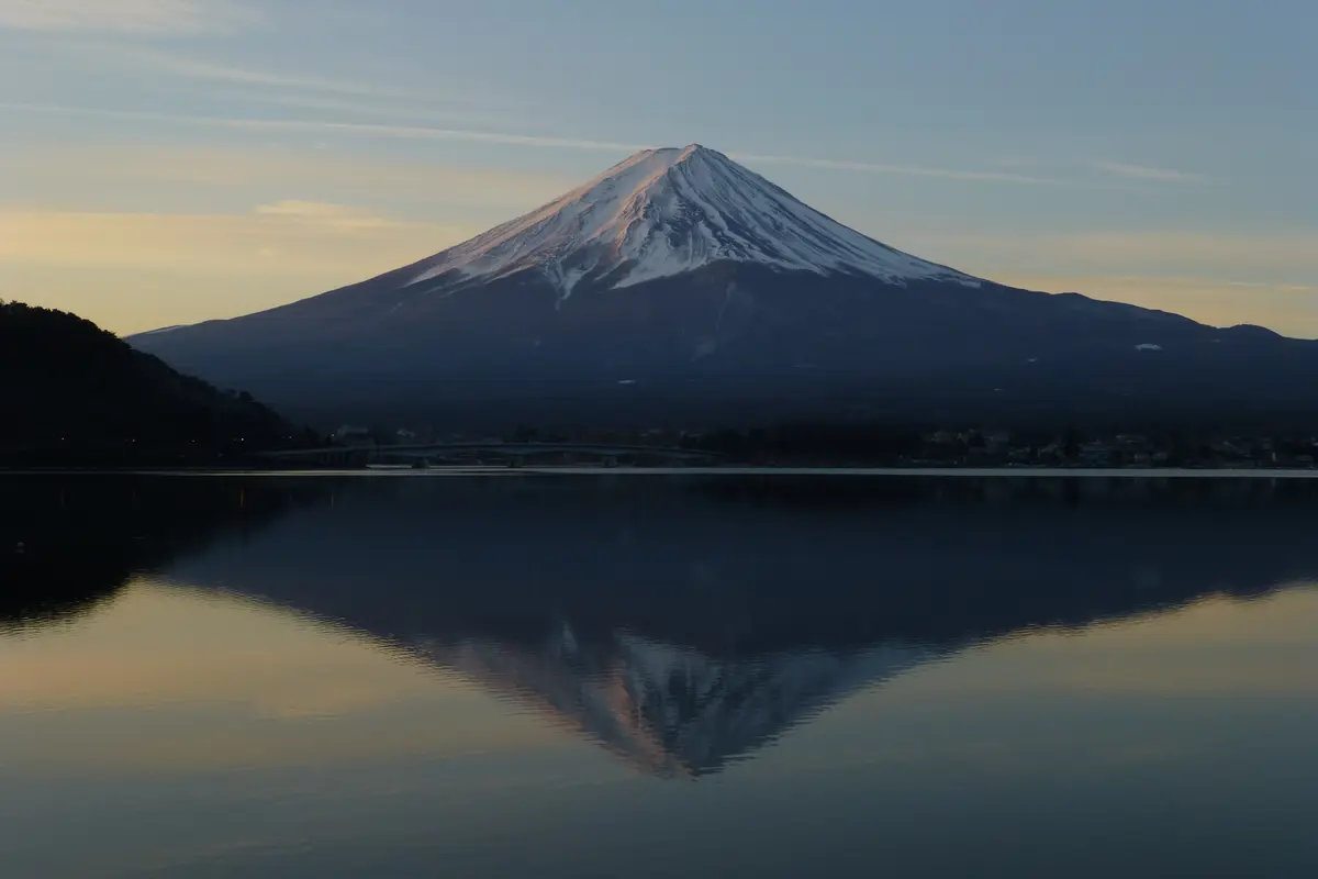 Vom Ufer des Kawaguchi-Sees im Januar: der ganze Kegel des Fuji spiegelt sich in einem Wasser ohne eine einzige Welle, dazwischen der Ort am See als dunkle Linie