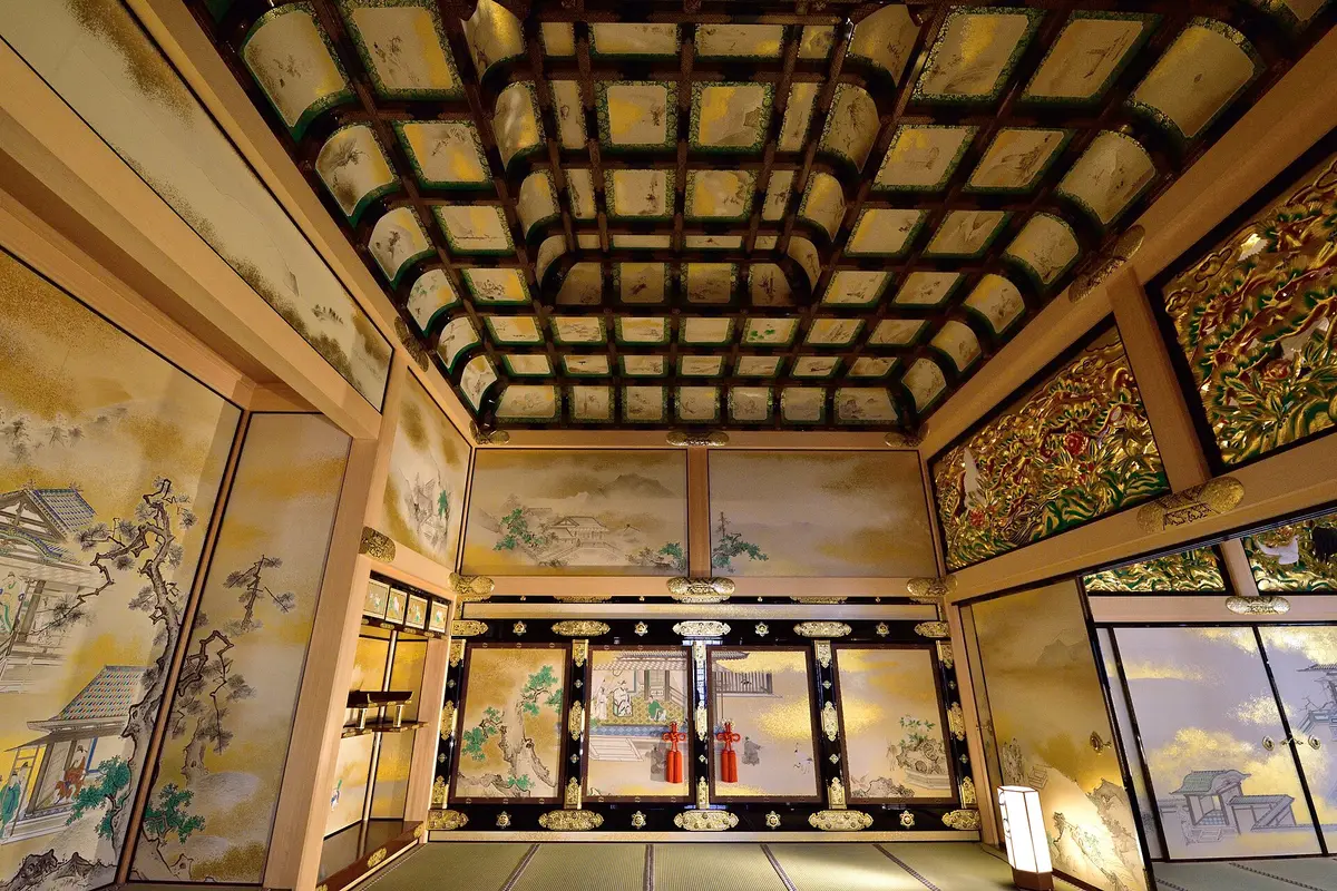 All'interno dell'Hommaru Palace restaurato: una stanza con tatami, soffitto a cassettoni dipinti, fregi intagliati e dorati sopra le porte, e pannelli scorrevoli dipinti su fondo oro con decorazioni metalliche