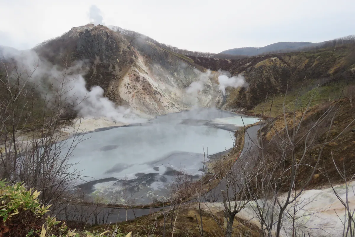 The steaming grey-green surface of Oyunuma, a crater pond in the hills above Noboribetsu Onsen