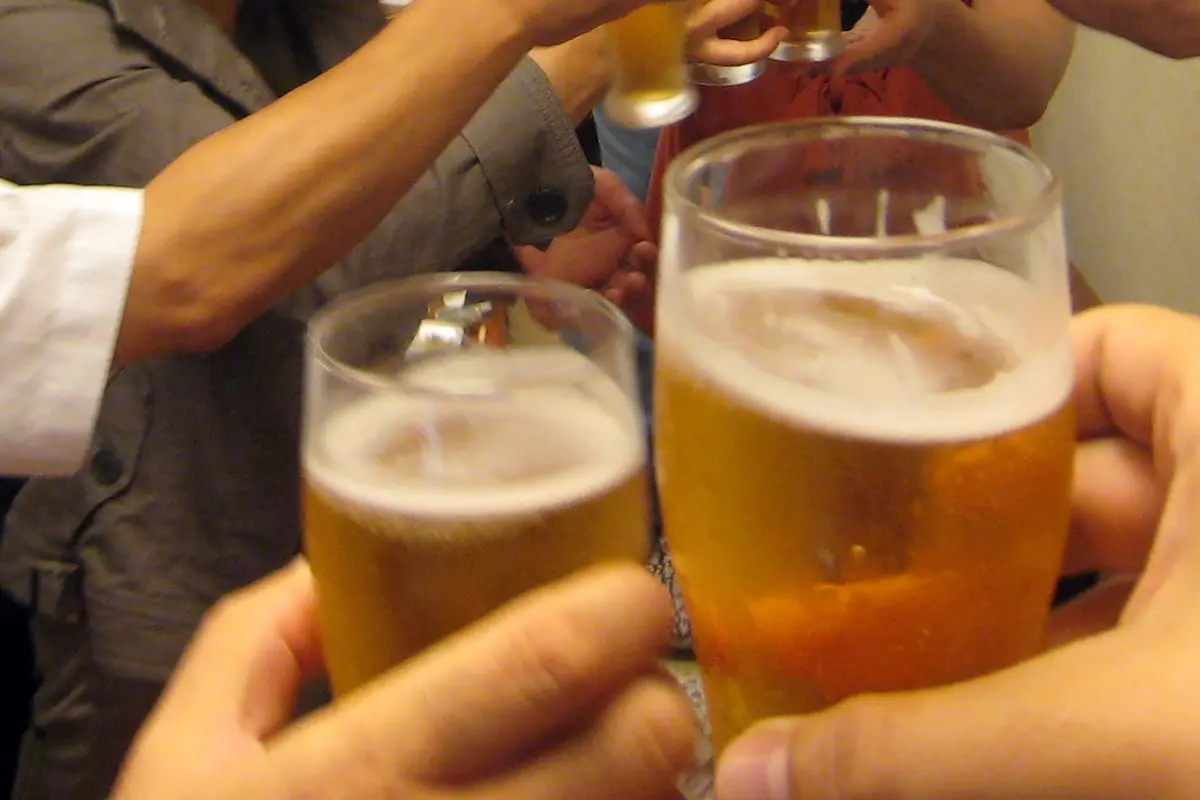Hands holding beer glasses clinked together at the start of a Japanese work gathering
