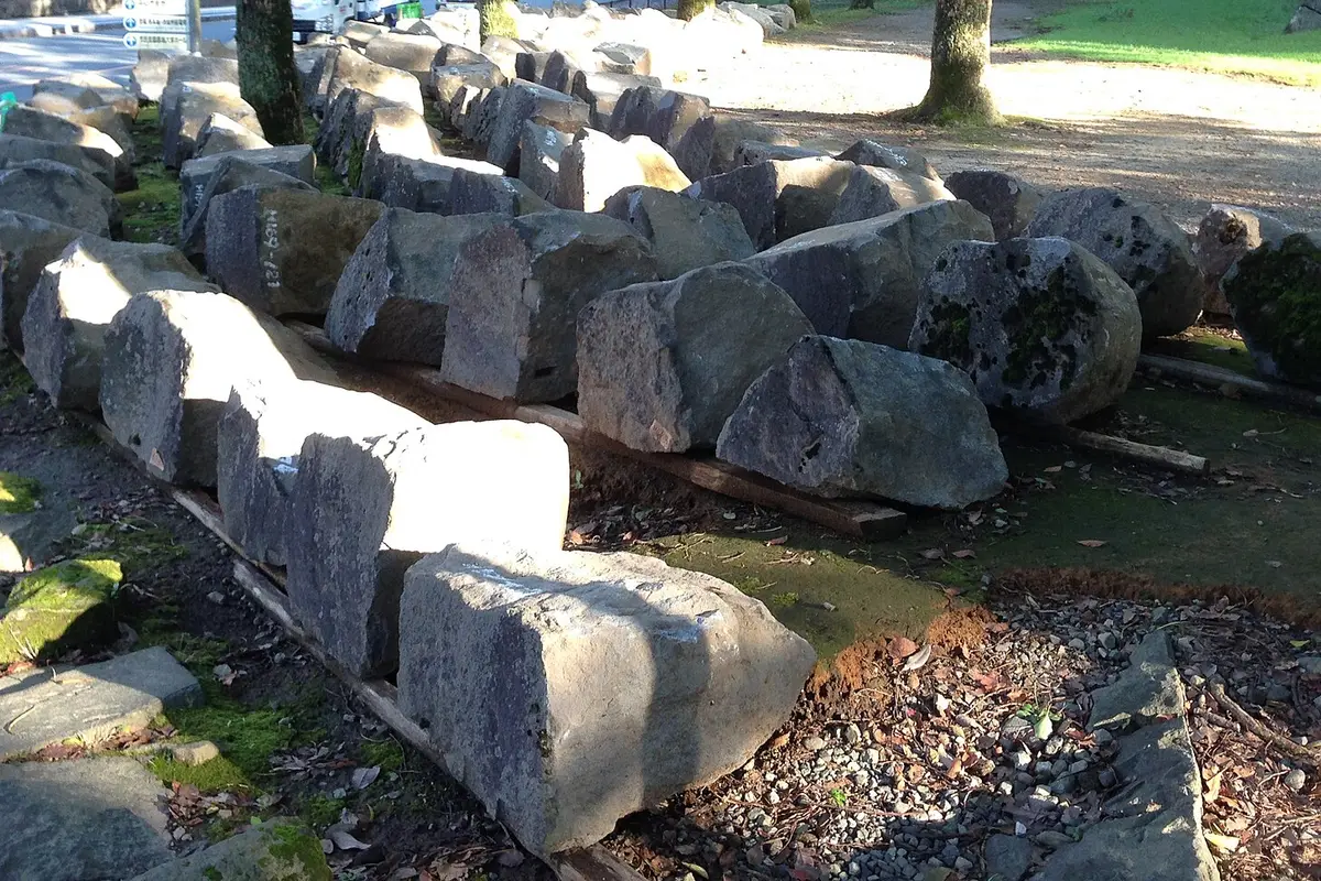 Rows of stones from Kumamoto Castle's collapsed walls resting on timber battens, each stone marked in white paint