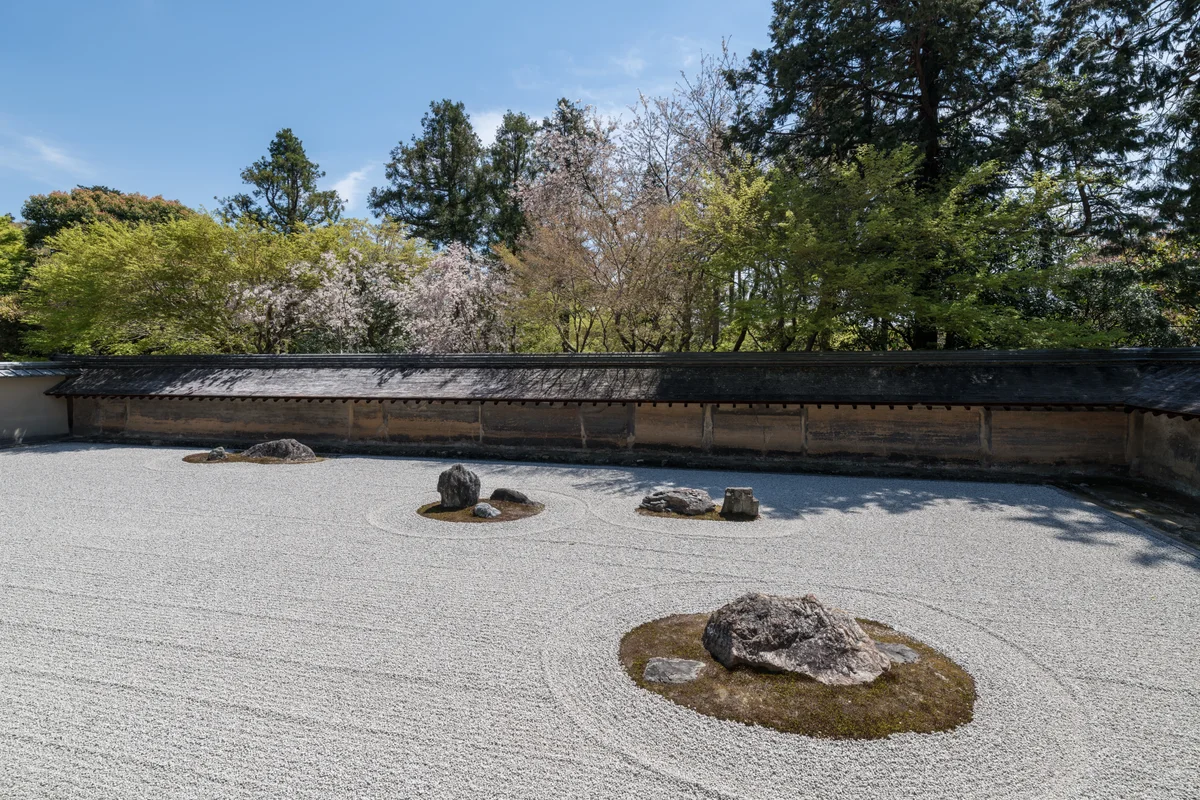 从寺院檐廊望出去的枯山水石庭，耙出纹路的白砂环绕着几组带青苔的石头