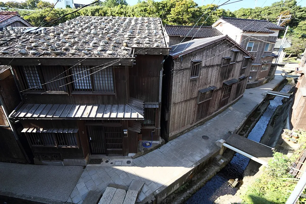 Un vicolo di pietra stretto tra case in legno di fasciame navale invecchiato nel villaggio di Shukunegi, isola di Sado