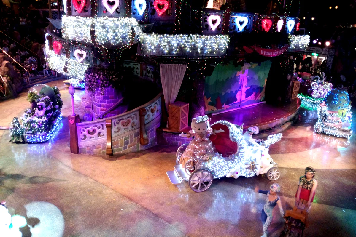 Hello Kitty su un carro illuminato durante una parata serale a Sanrio Puroland, con un palco illuminato alle sue spalle