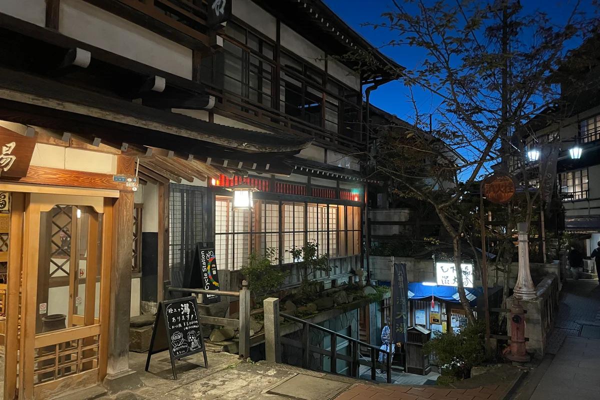 Twilight view down the steps to Oyu, the ninth public bath in Shibu Onsen, with a lone figure in yukata at the entrance