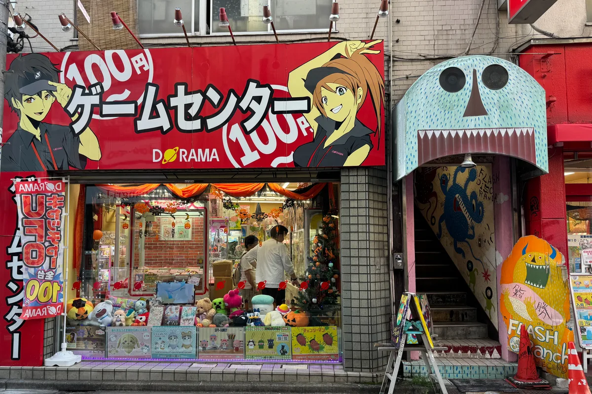 หน้าร้านเกมตู้ขนาดเล็กทาสีสดใสในซอยแห่งหนึ่งของชิโมคิตะซาวะ มีป้ายร้านและตุ๊กตาของรางวัลวางโชว์อยู่ที่หน้าต่างร้าน