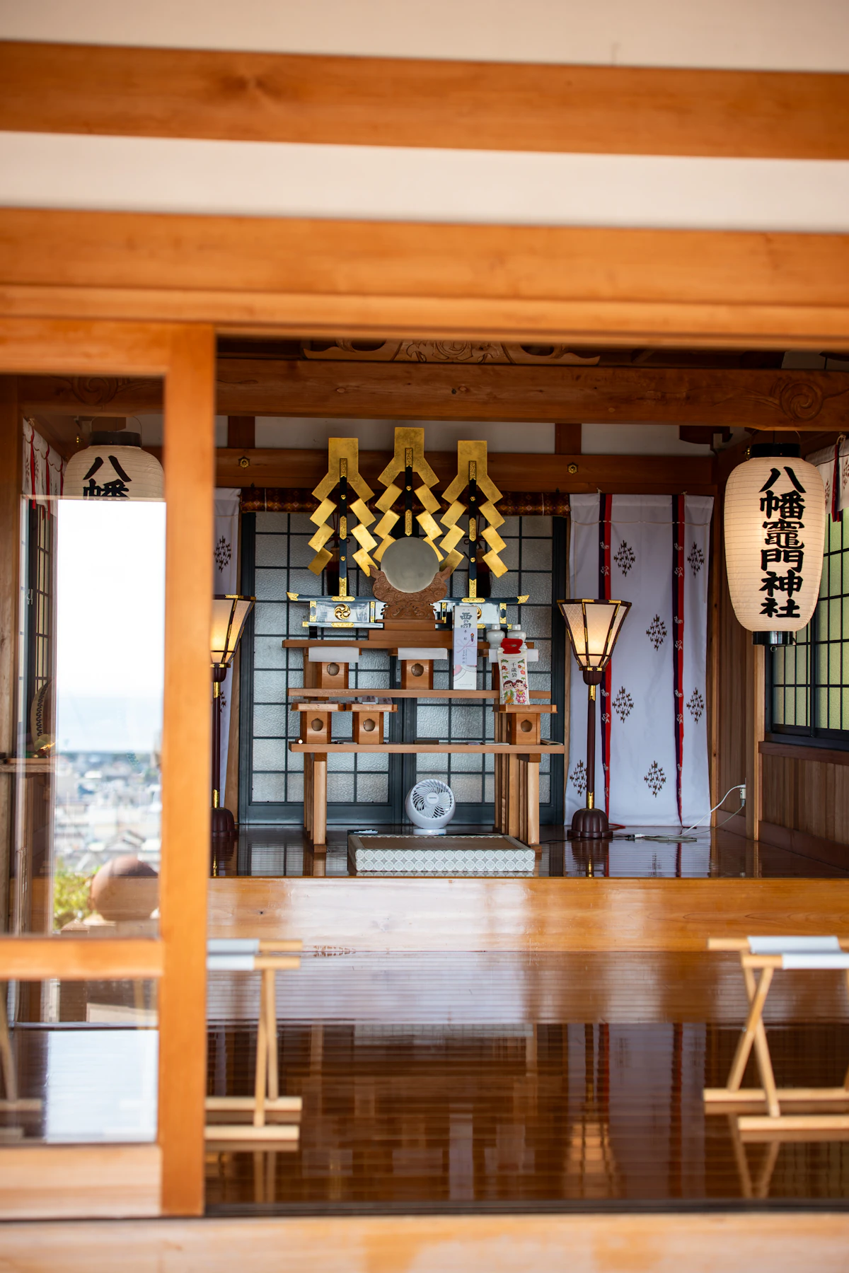 The serene interior of a Hachiman shrine with golden ornaments and paper lanterns