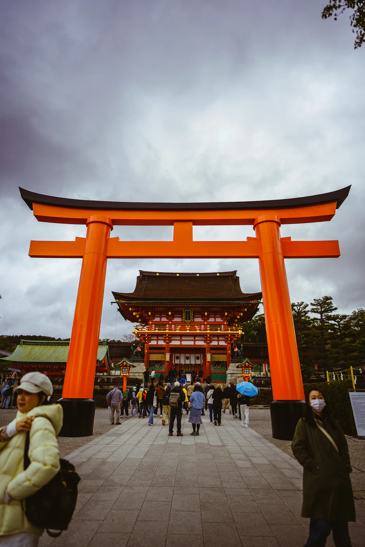 Visitors walking through the grand torii gate at Fushimi Inari Shrine in Kyoto