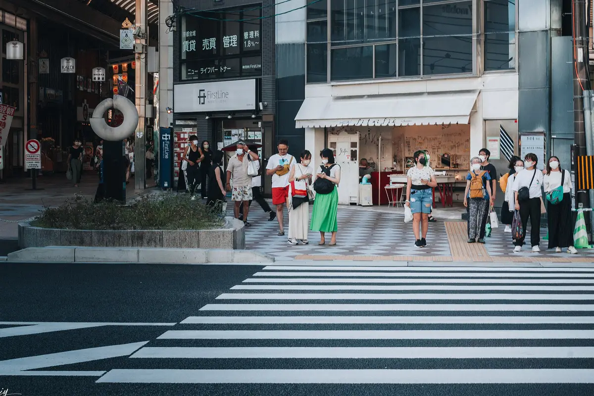 People waiting on the far side of a crosswalk on a city street in Japan