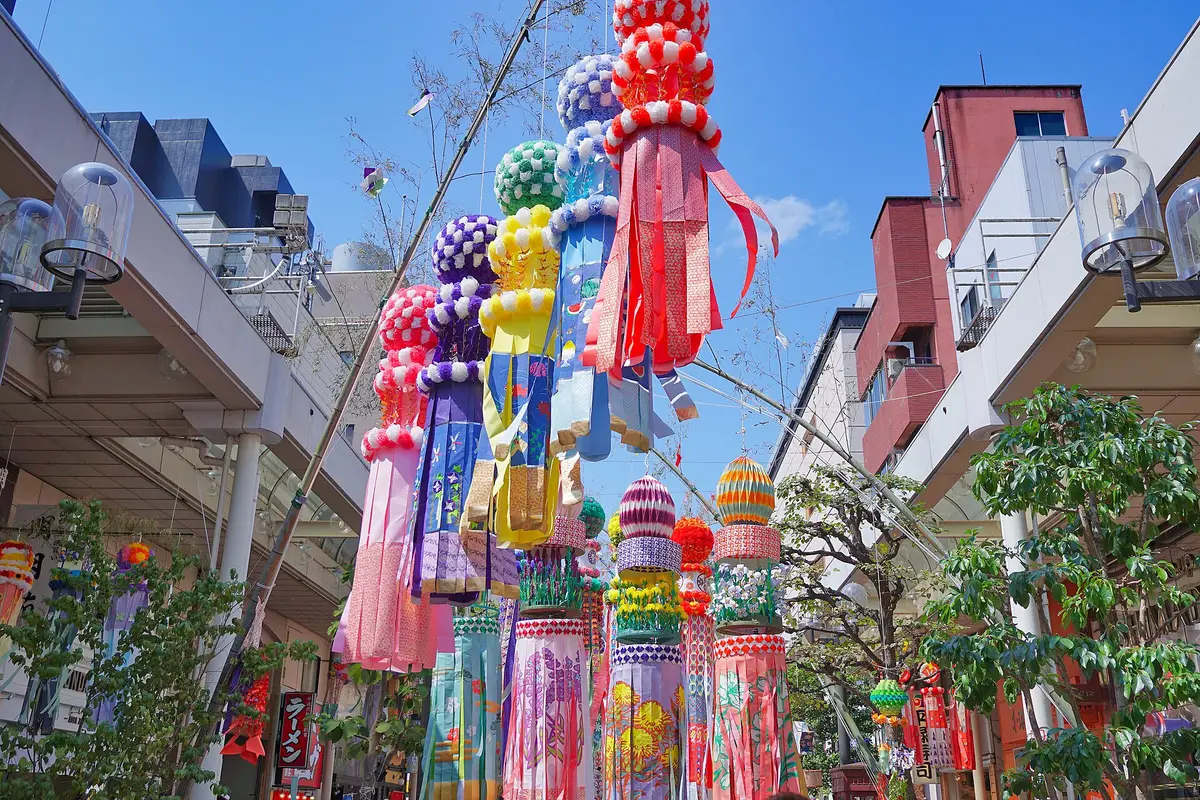 Giant paper streamers topped with colorful pom-poms hanging above a shopping street at the Sendai Tanabata Festival