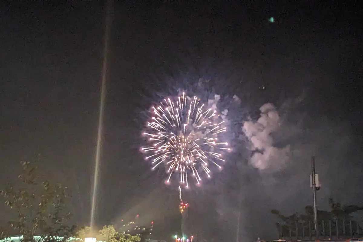 A single firework bursting high in the night sky above the Tenjin Matsuri riverside