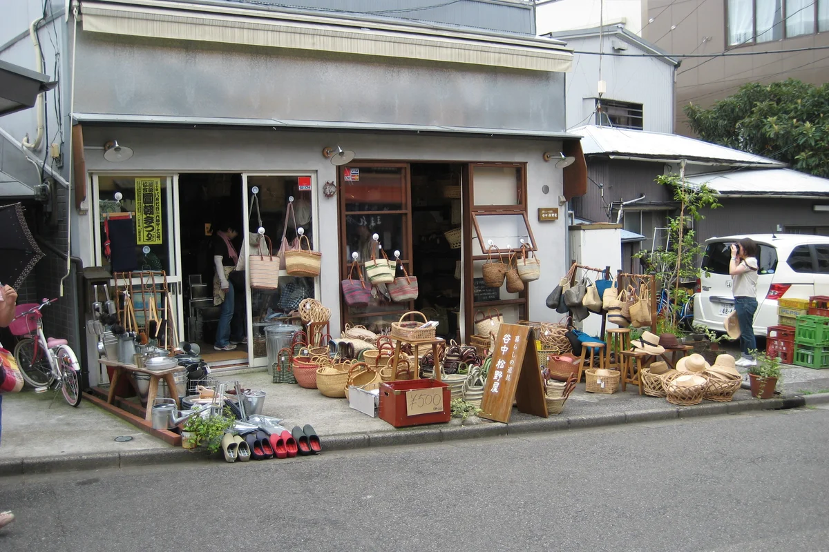 A basket and craft shop on Yanaka Ginza with handwoven bags and goods displayed on the pavement outside, and bicycles parked nearby
