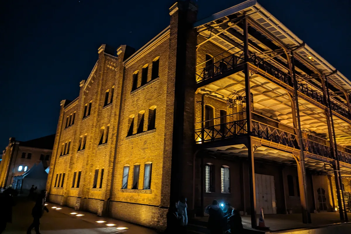 The Yokohama Red Brick Warehouse lit up at night, its brick facade and iron balconies glowing against the dark sky