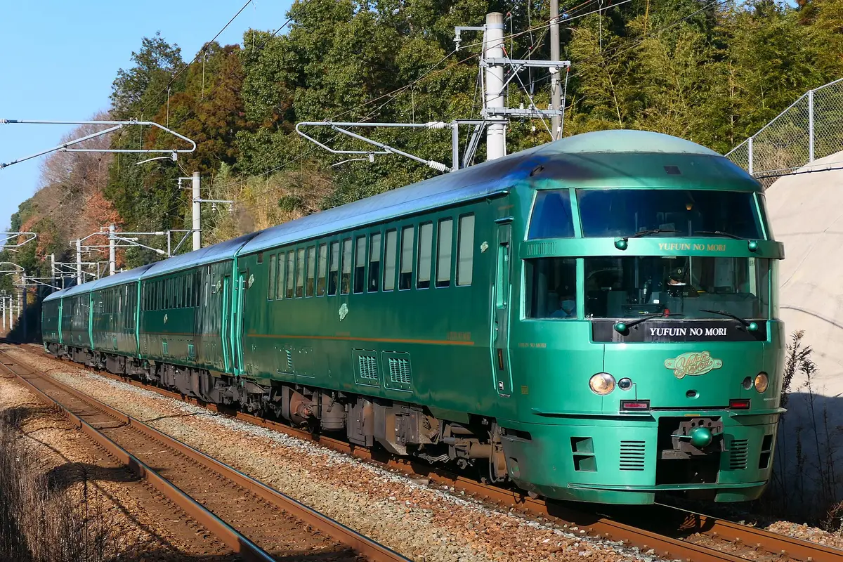 Il Limited Express Yufuin no Mori, verde, visto di lato sui binari, con in testa la carrozza dal muso arrotondato