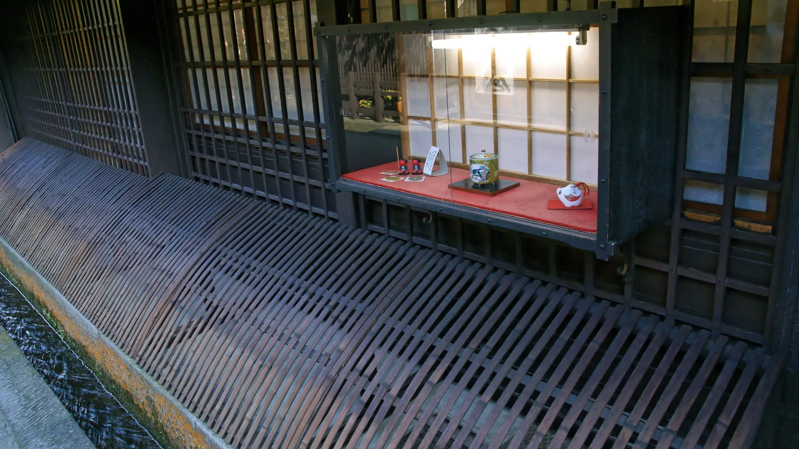 Latticed wooden shopfronts and a water channel along a street in the Sanmachi old town of Takayama